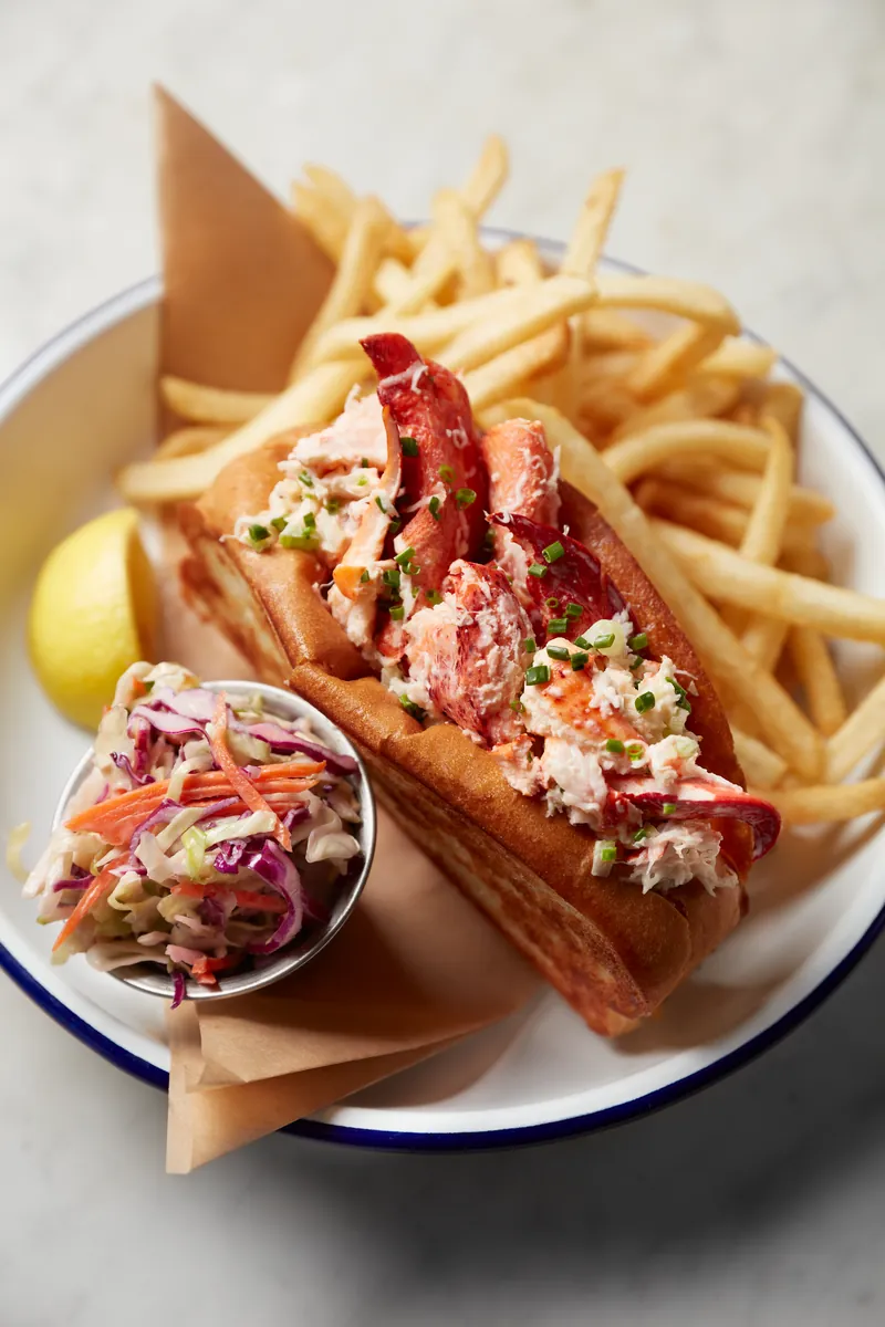 Lobster roll served with fries, coleslaw, and a lemon wedge