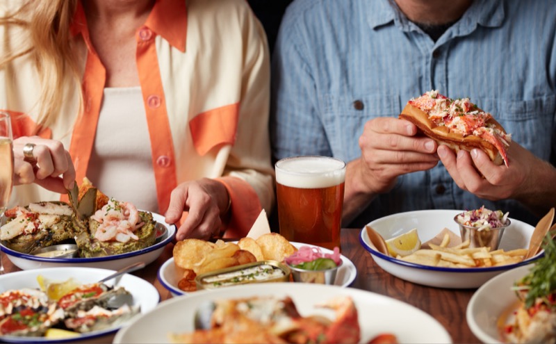 Couple enjoying lobster rolls and beer